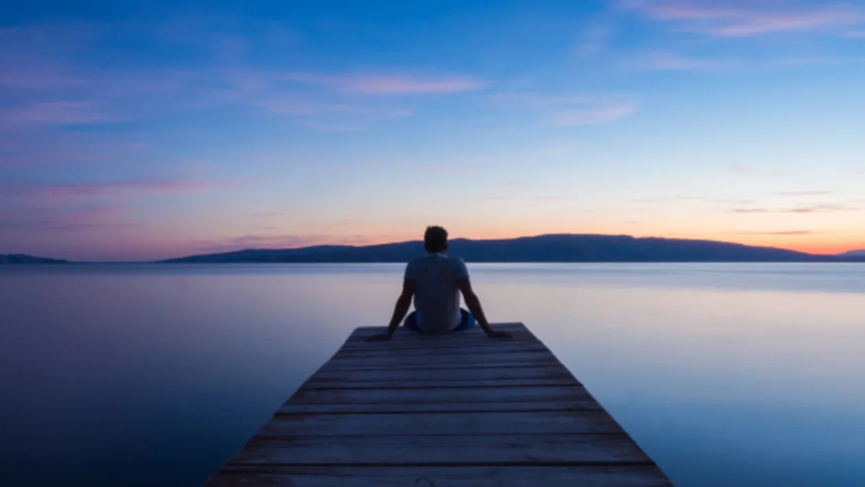 man in contemplation on dock for spiritual wellness